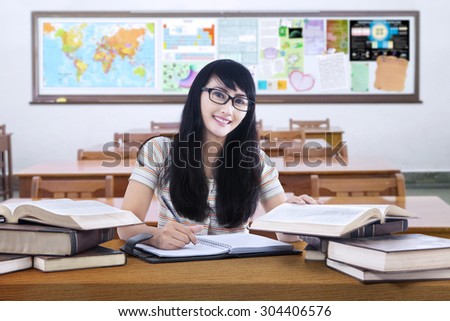 Portrait of beautiful high school student with long hair, studying in the classroom and smiling at the camera