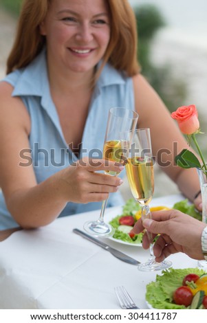 Close-up picture of red-haired man smiling to her husband. People sitting in the restaurant and drinking wine from glasses.