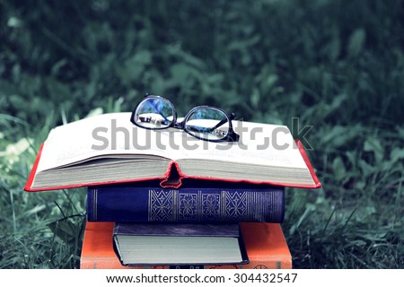 Open book with glasses on nature background. Vintage style. Knowledge is power Royalty-Free Stock Photo #304432547