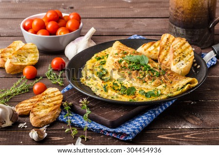 Herb omelette with chives and oregano sprinkled with chili flakes, garlic panini toasts Royalty-Free Stock Photo #304454936