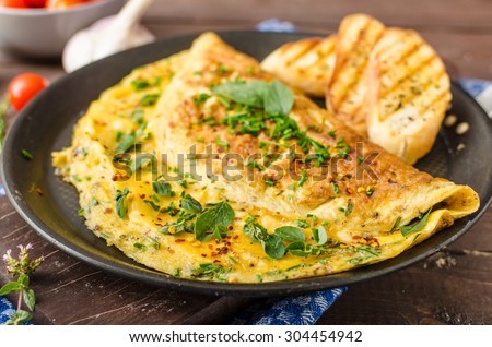 Herb omelette with chives and oregano sprinkled with chili flakes, garlic panini toasts Royalty-Free Stock Photo #304454942
