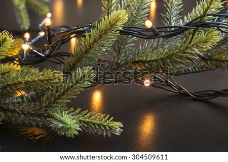 Fir-tree branches and flash lights on wooden background