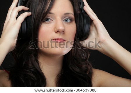 young woman listening to music on headset black background