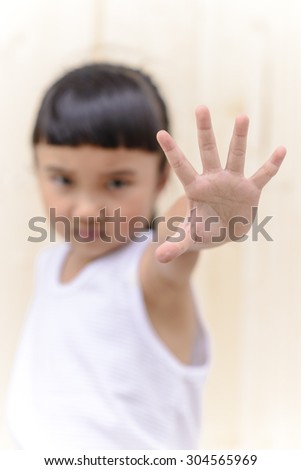 Kid make stop symbol and blur serious face on wall background