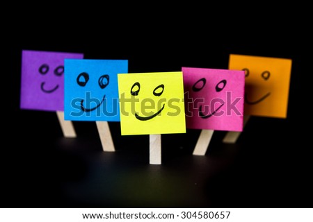 sticky notes with happy faces isolated on a black background for a happy team concept