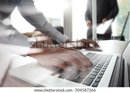 Close up of business man hand working on laptop computer with business strategy diagram on wooden desk as concept