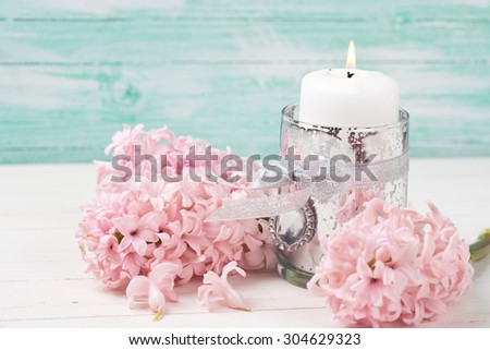 Hyacinths flowers and candle on white wooden background against turquoise wall. Selective focus. Place for text.