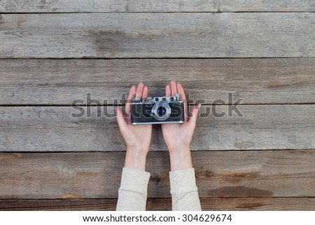 Hand holding a retro camera over wooden table