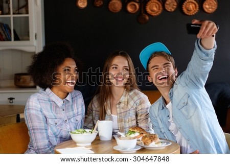 Cheerful multiracial friends taking selfie in a cafe 