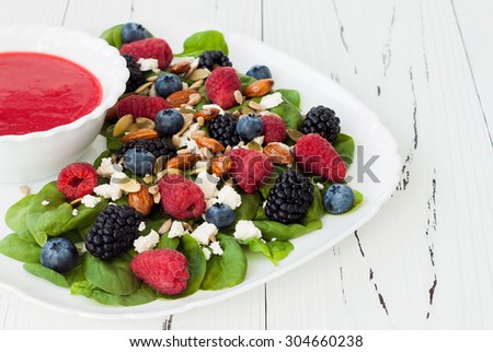 Summer refreshing spinach mixed berry salad with pumpkin and sunflower seeds, almonds, feta cheese and sweet red raspberry vinaigrette
