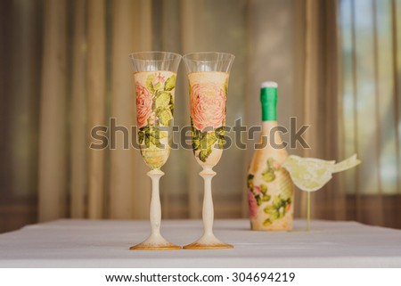 two decorative champagne glasses with bottle and bird on the table