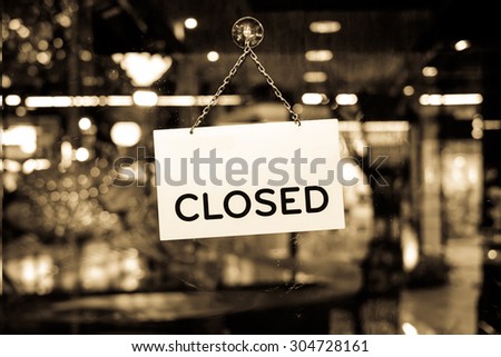 A closed sign hanging in a shop window with retro effect filter