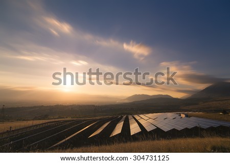 Landscape picture of a solar plant that is located inside a valley surrounded by mountain during the sunset.
