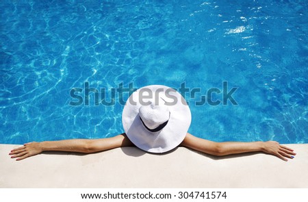 Woman in white hat relaxing at the pool 