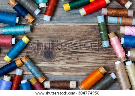coils of different threads on the surface of an old tailors table