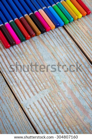 colored pencils on blue old wooden background