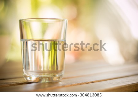 glass of water on wooden table bokeh background - vintage style picture Royalty-Free Stock Photo #304813085
