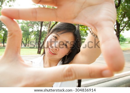 Beautiful asian woman make a frame shot symbol with her hands on white.