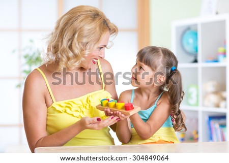 kid girl and mother playing at table at home