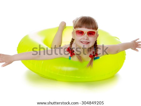 The little blonde girl in the pink glasses. The girl is in a swimsuit on a yellow rubber ring for swimming, spreading their arms . The girl is vacationing with his parents in the seaside resort