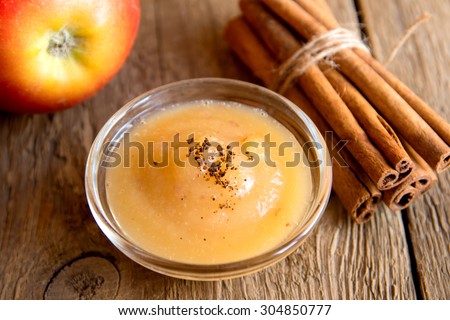 Fresh homemade applesauce (apple puree, mousse, baby food, sauce) with cinnamon (spices), spoon and apples on wooden table close up, horizontal Royalty-Free Stock Photo #304850777