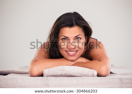 Cheerful woman lying on massage lounger in a wellness center and looking at camera
