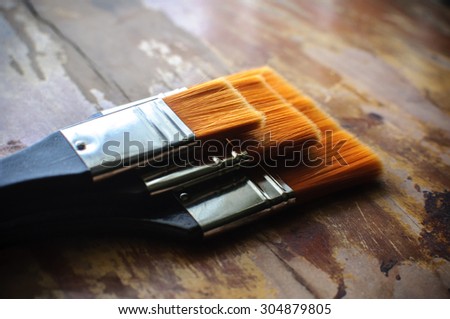 Paint brush or paintbrush resting on the wooden floor.