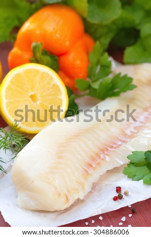 Raw fish with vegetables, lemon and seasonings on the wooden table