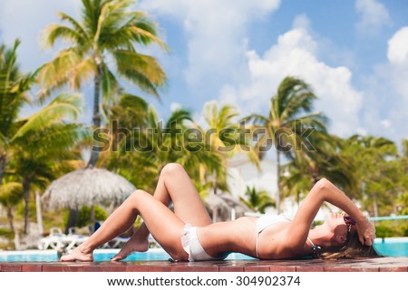 young woman relaxing by the tropical pool