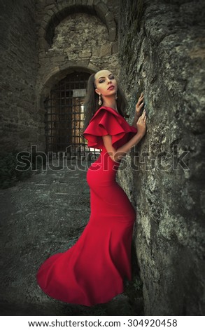 Elegant woman in red dress near castle 