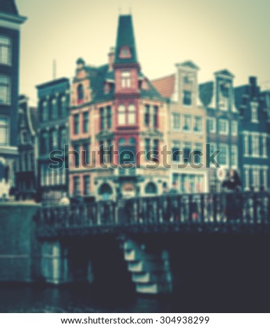 Amsterdam houses and bridge over the canal in cloudy day. Blurred toned photo.