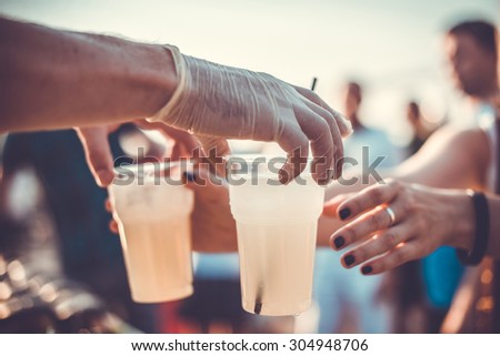 Hands with two plastic glasses of lemonade. Toned picture