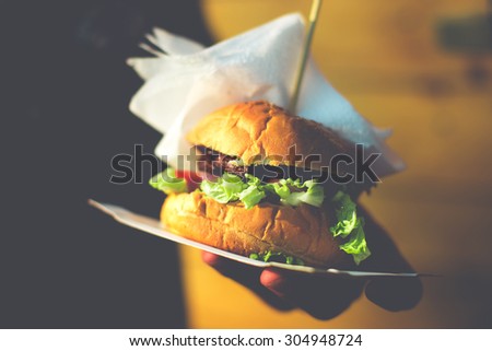 Closeup of home made burger in hand. Toned picture
