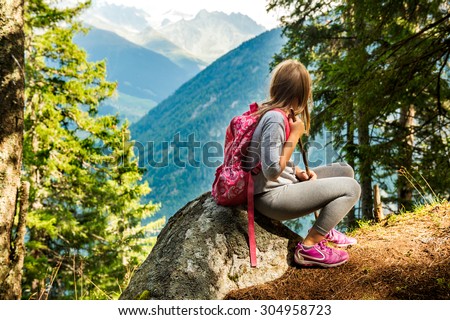 Cute little girl hiking in swiss Alps, resting on a rock and admire amazing view Royalty-Free Stock Photo #304958723