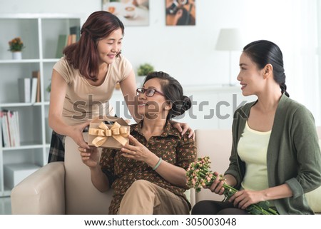 Daughter and granddaughter congratulating grandmother with her birthday