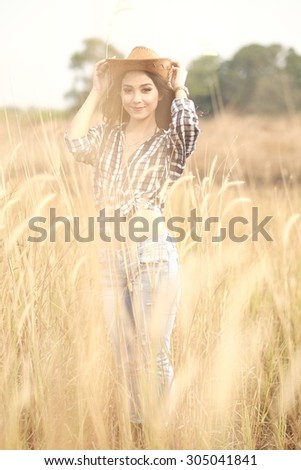 Beautiful Asian Girl in the reed prairie holding cowboy hat
