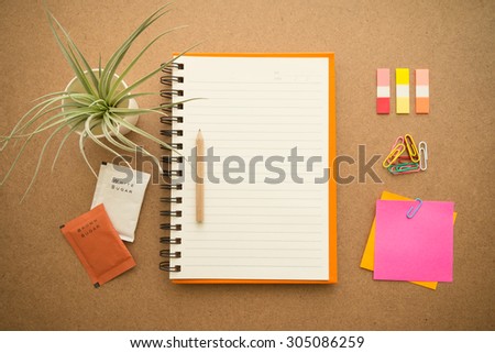 Blank notepad with office supplies on wooden table. Top view