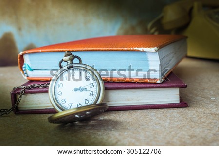 Stopwatch and book on the old wooden table.