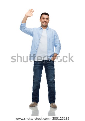 happiness and people concept - smiling man in shirt and jeans waving hand Royalty-Free Stock Photo #305123183