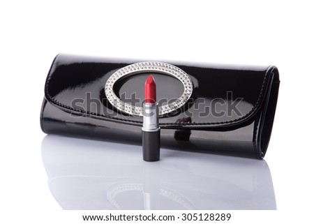 Black handbag clutch and classic red lipstick, isolated on white background with reflection