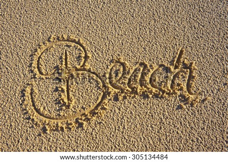 The word 'Beach' hand written in the sand. Summer vacation concept.