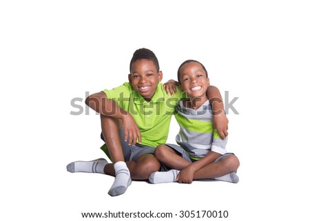 2 school aged brothers sitting on the floor looking at the camera with their arms around each other
