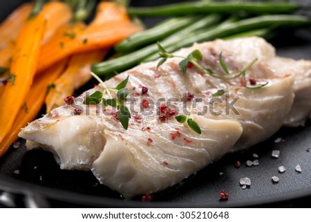 grilled fish with green beans and carrots on frying pan