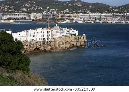 Typical constructions of white houses in the town of Ibiza, Watch tower at the entrance to the port of Ibiza, Hotels along the beach, places to stay, Ocean waves crash on shore, white houses,