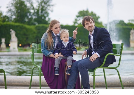 Happy family of three in the beautiful garden of Palais Royal in Paris on a summer day
