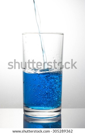pouring blue drink splash into glass on white background