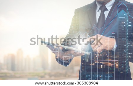 Double exposure of businessman using the tablet with cityscape and financial graph on blurred building background, Business Trading concept Royalty-Free Stock Photo #305308904