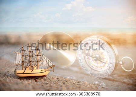 Double exposure of sailboat on the beach with vintage compass 