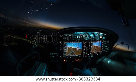 Lightened up cockpit and avionics in aircraft flying at night with beautiful twilight in background Royalty-Free Stock Photo #305329334