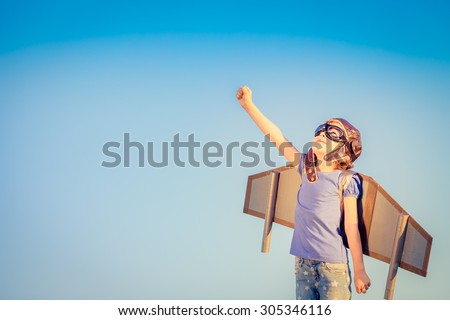 Happy child playing with toy wings against summer sky background Royalty-Free Stock Photo #305346116
